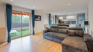 A modern living room with a large sofa, a dining area, and a kitchen in the background. - Comfortable Apartment with large sunny terrace (Niza)