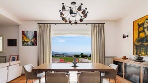 Un comedor con vistas al exterior, una araña y un cuadro en la pared.