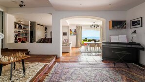Un amplio salón con un tablero de ajedrez, un piano y vistas al exterior.