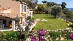 Una villa de estilo mediterráneo con jardín, mobiliario exterior y vistas del paisaje circundante.