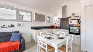 Un espacio habitable compacto con kitchenette, comedor y sofá con una manta roja.