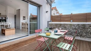 Un patio con mesa lista para comer, sillas plegables y una terraza de madera.