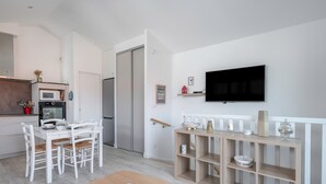 Una cocina moderna con armarios blancos, microondas y un comedor con mesa y sillas de madera.