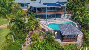 Une grande maison à plusieurs étages, dotée d’une piscine et d’un jardin luxuriant.
