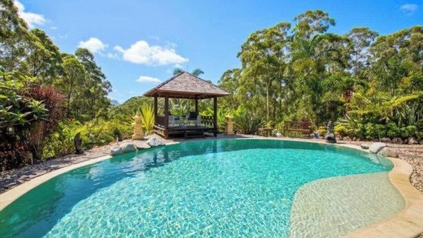Une piscine d’un bleu éclatant, agrémentée d’un belvédère et d’une végétation luxuriante.