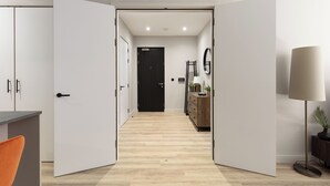 A modern hallway with a wooden floor, white walls, and a black door at the end. - The Brickworks - Grade II Boutique Stay, 2 Bed. (Birmingham)