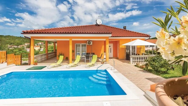 Una casa con piscina, paredes amarillas y techo rojo.