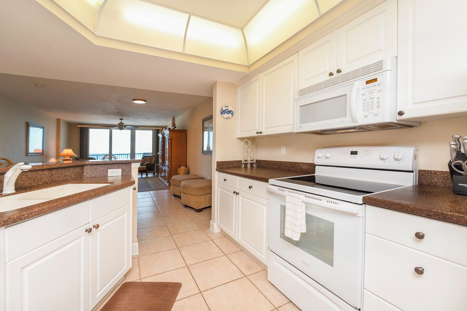 A kitchen with white cabinets, a microwave, a stove, and a sink.