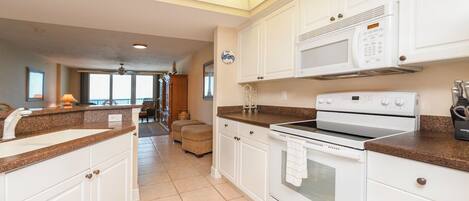 A kitchen with white cabinets, a microwave, a stove, and a sink.