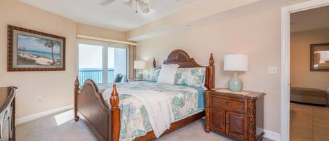 A bedroom with a wooden bed, a nightstand, a ceiling fan, and a view of the outdoors.