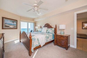 A bedroom with a wooden bed, a nightstand, a ceiling fan, and a view of the outdoors.