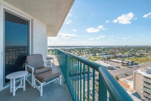 En balkon med stol og bord, med udsigt over et boligområde med huse og en klar himmel.
