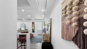 Un interior moderno con zona de comedor, un reposapiés negro y un tapiz decorativo.