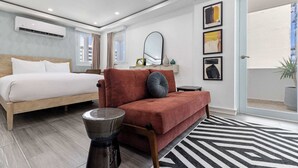 Un dormitorio moderno con una cama, un sofá, una mesita y un espejo.