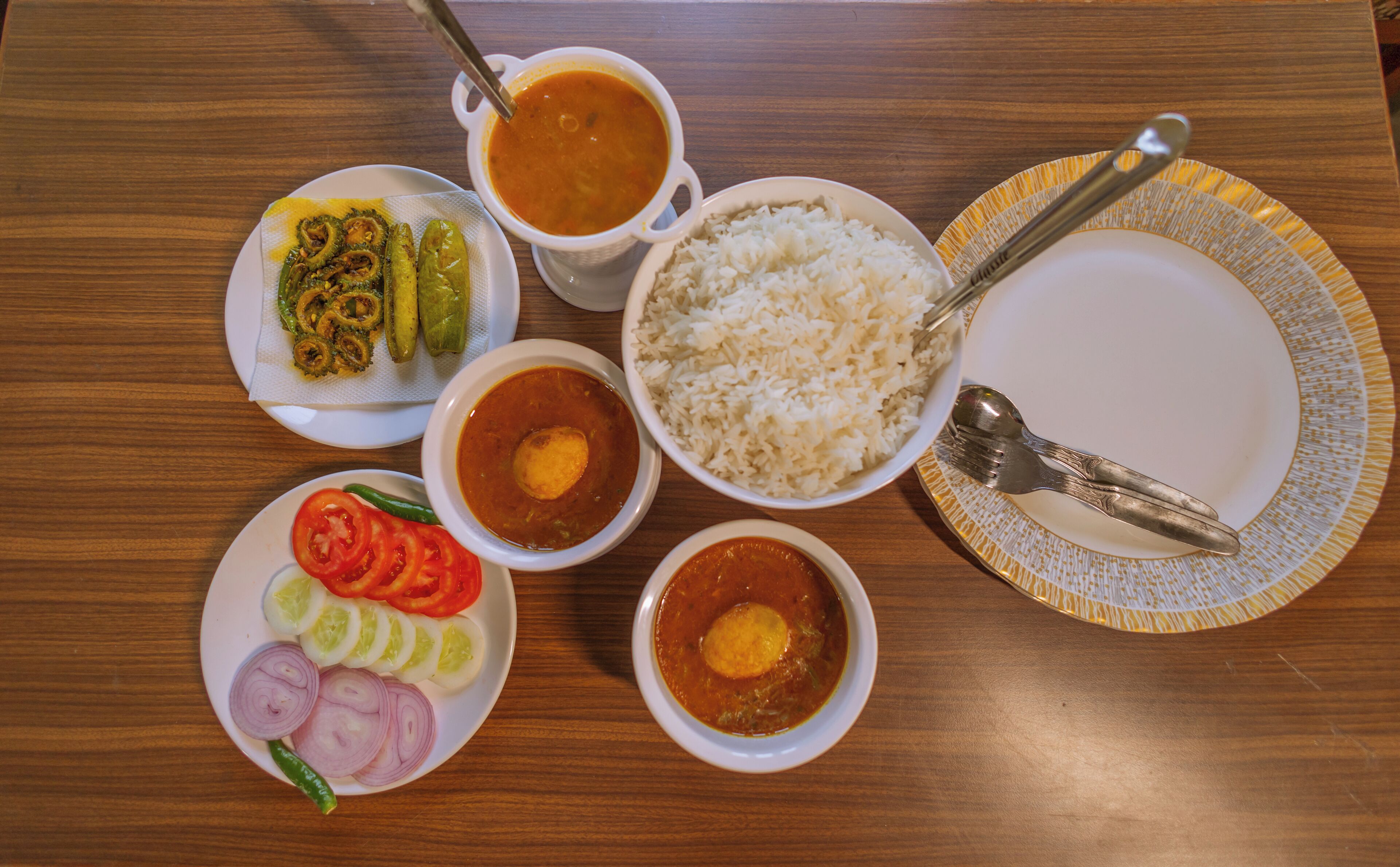 Una mesa con diversos platos, incluyendo arroz, curry y verduras.