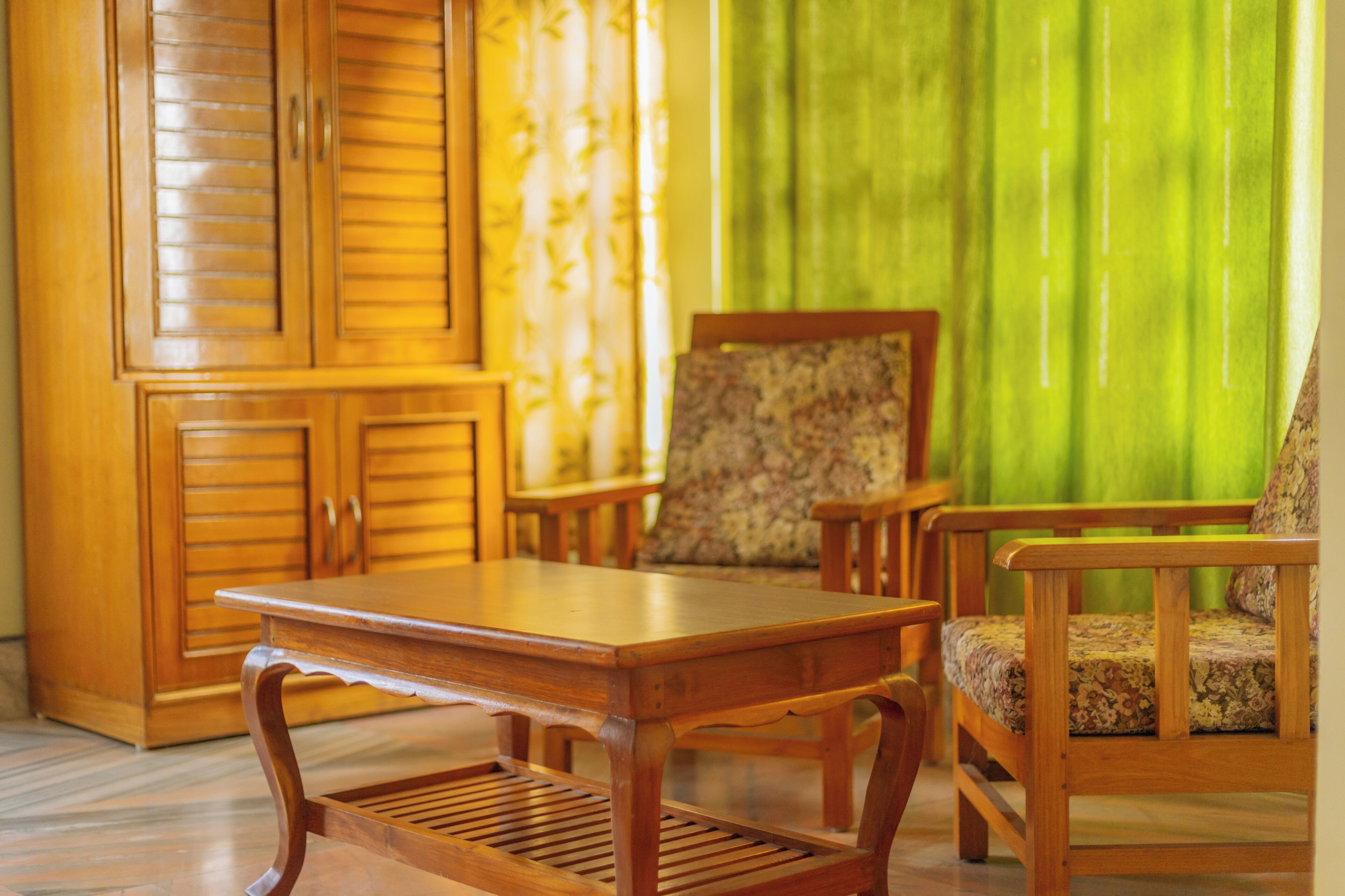A wooden table and chairs in a room with a green curtain and a wooden cabinet.