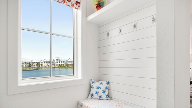 A room with a large window overlooking a body of water and houses.