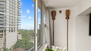 Een moderne hotelkamer met een groot raam met uitzicht op de stad, een potplant en twee houten scheen op de muur.