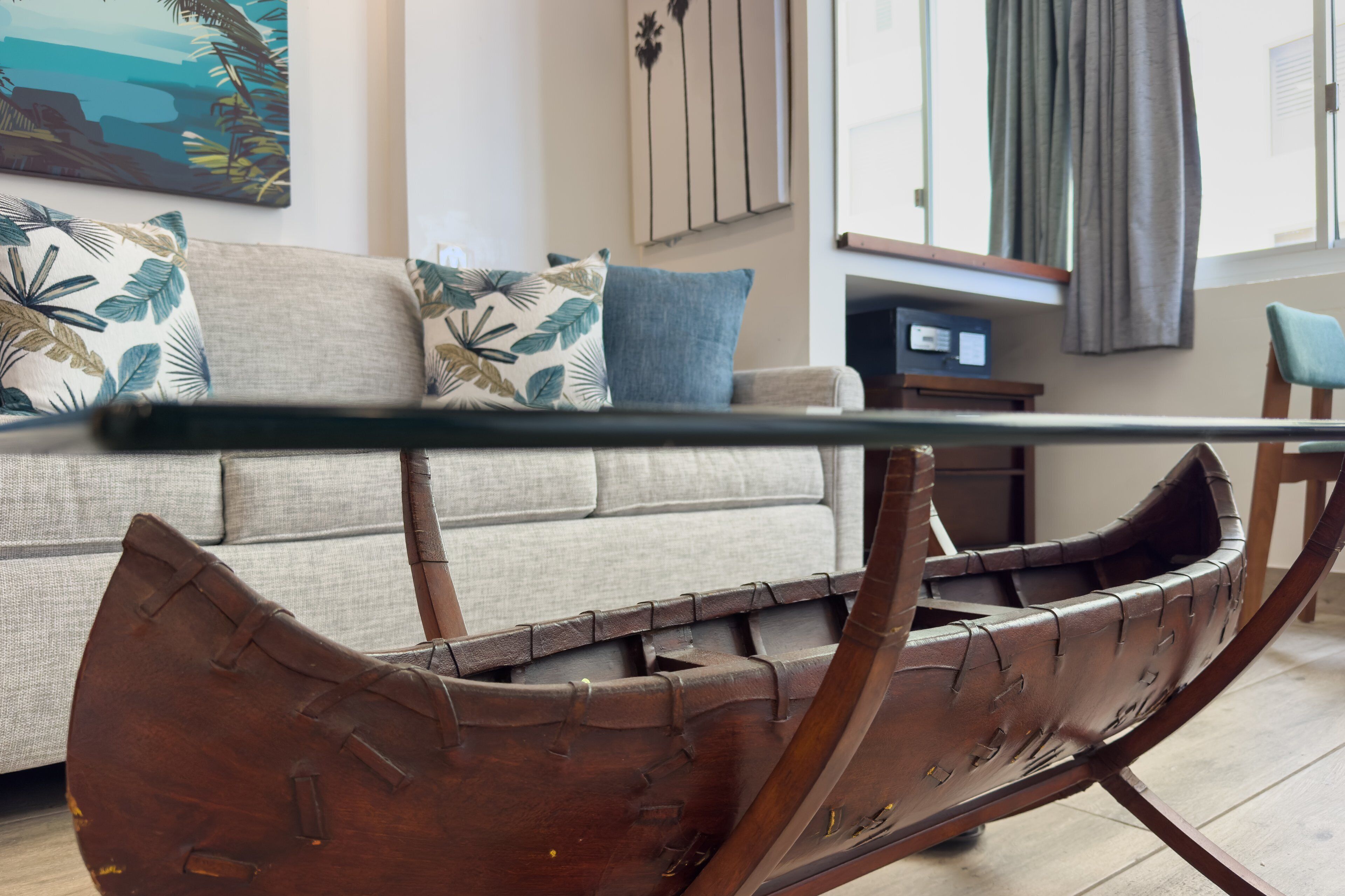 Un fauteuil en bois, dans un salon moderne, avec un canapé et des coussins.
