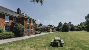 A brick building with a lawn and a picnic table. - Bonington Student Village - Campus Accommodation (Sutton Bonington)