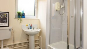 A bathroom with a white sink, a window above it, and a glass-enclosed shower area. - Bonington Student Village - Campus Accommodation (Sutton Bonington)