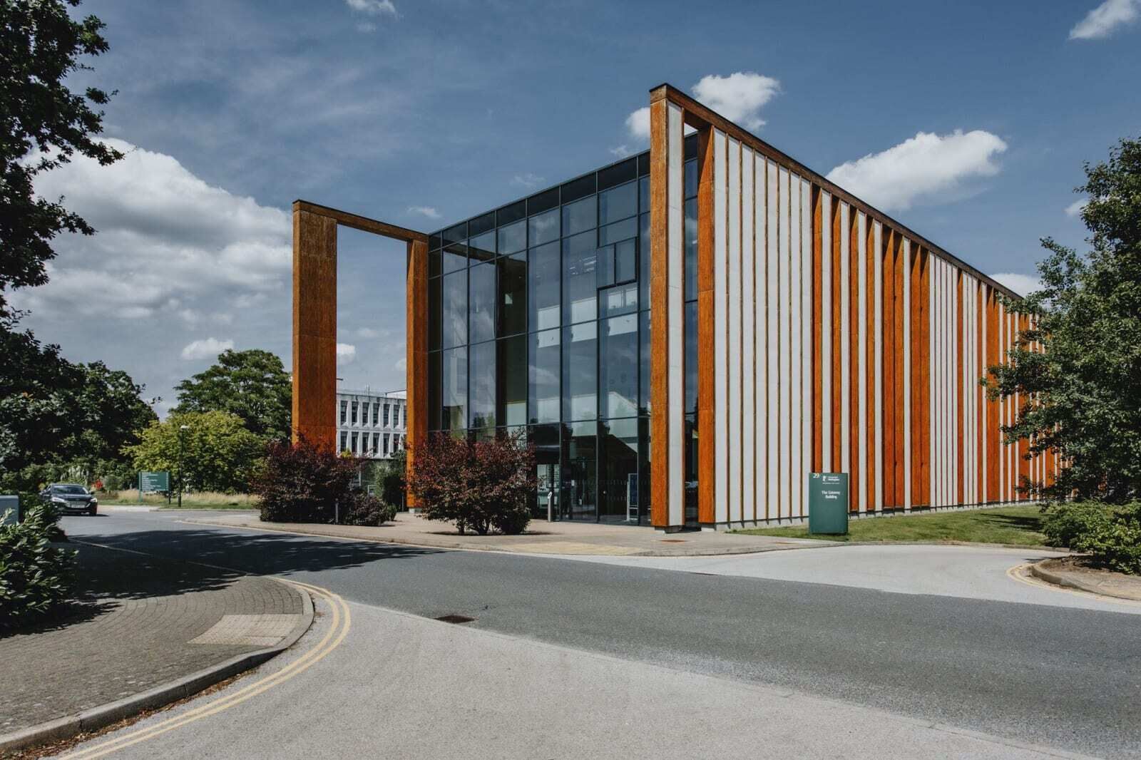 Un bâtiment moderne doté de grandes fenêtres en verre et d’une façade en bois.