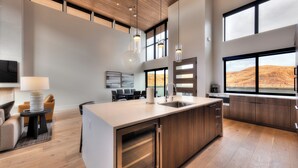 A modern kitchen with a large island, built-in appliances, and a dining area with a view. - Slickrock Luxury Retreat | Panoramic Views | Min to Trails and Ntl Parks (Moab)