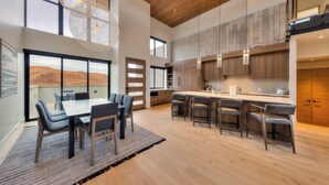 A spacious kitchen with a large island, wooden cabinets, and a view of the desert. - Slickrock Luxury Retreat | Panoramic Views | Min to Trails and Ntl Parks (Moab)