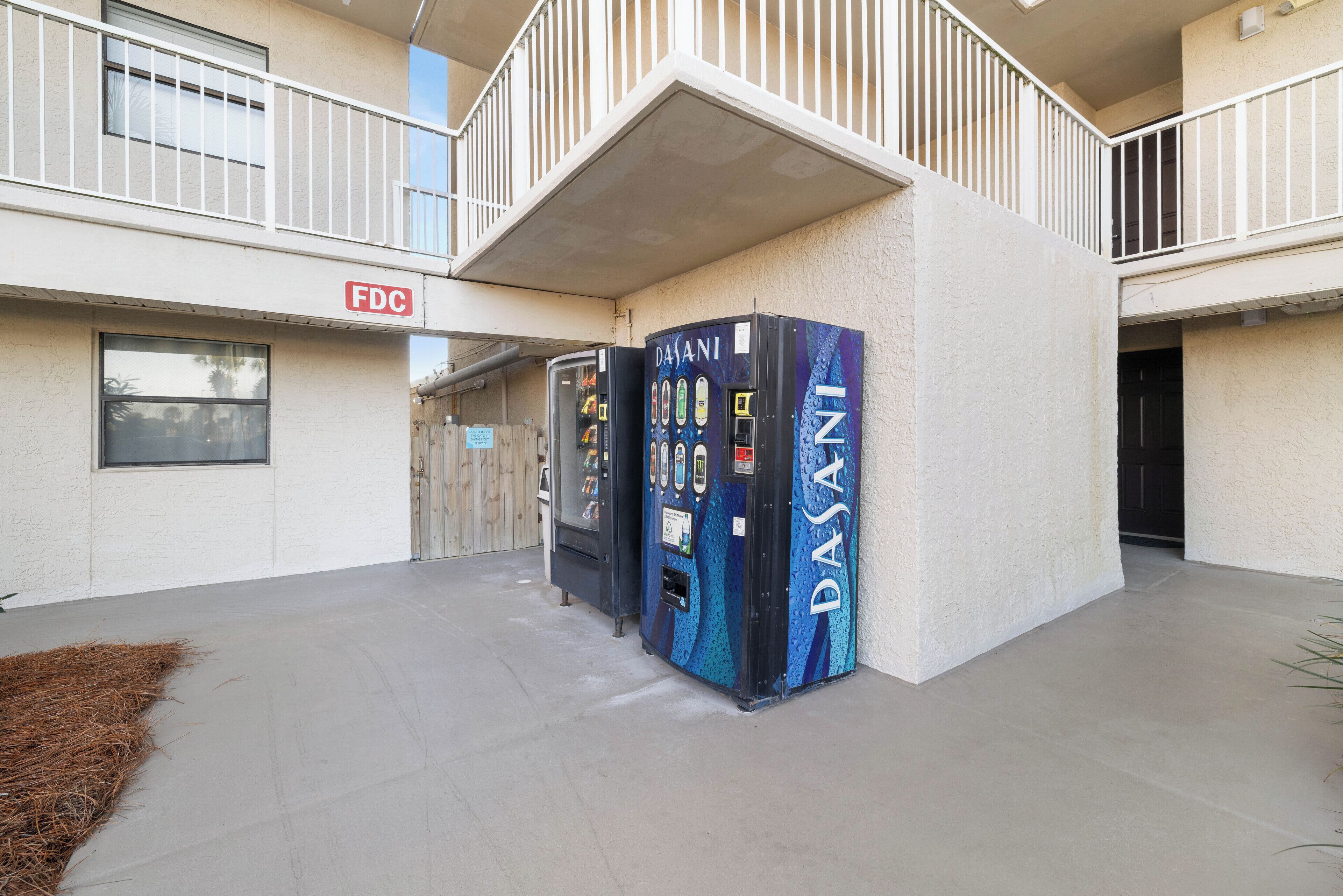 A building exterior with a sign reading "FDC" and two vending machines labeled "DASANI".