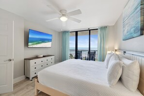 A bedroom with a bed, a ceiling fan, a TV, a dresser, and a balcony with a view of the ocean. - Seaside Beach & Racquet 5615 by Liquid Life (Orange Beach)