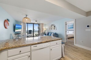 A modern kitchen with granite countertops, a dishwasher, and a dining area with chairs and a table. - Seaside Beach & Racquet 5615 by Liquid Life (Orange Beach)