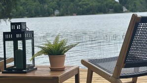 Une terrasse en bois avec une table et une chaise, une plante en pot et une lanterne.