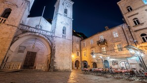 A historic building with a clock tower, a courtyard with outdoor seating, and a sign for the "LE GALLERY" restaurant. - Central Cathedral Apartment (Kotor)
