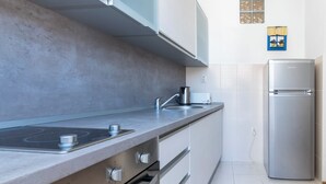 A modern kitchen with a stainless steel refrigerator, a built-in oven, and a stovetop. - Central Cathedral Apartment (Kotor)