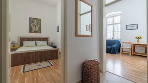 A bedroom with a wooden bed, a bedside table, a lamp, and a framed picture on the wall. - Central Cathedral Apartment (Kotor)