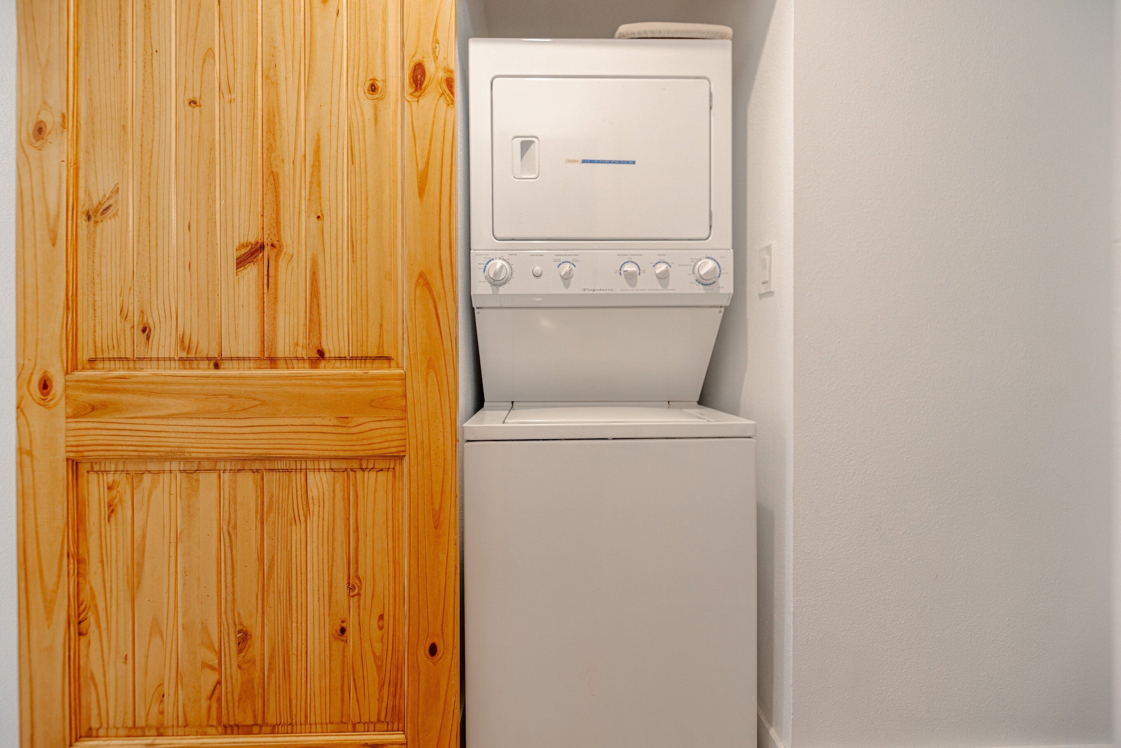 A laundry room with a wooden door and a white washing machine.