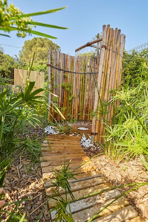A wooden pathway leading through a bamboo fence with a small stream. - Villa Filao with infinity pool 10 minutes from the beaches of Argeles sur mer. (Sorède)