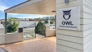 A gated entrance to a building with a sign reading "OWL Quality Apartments" and an owl logo. - Casa Barbara (Chania)