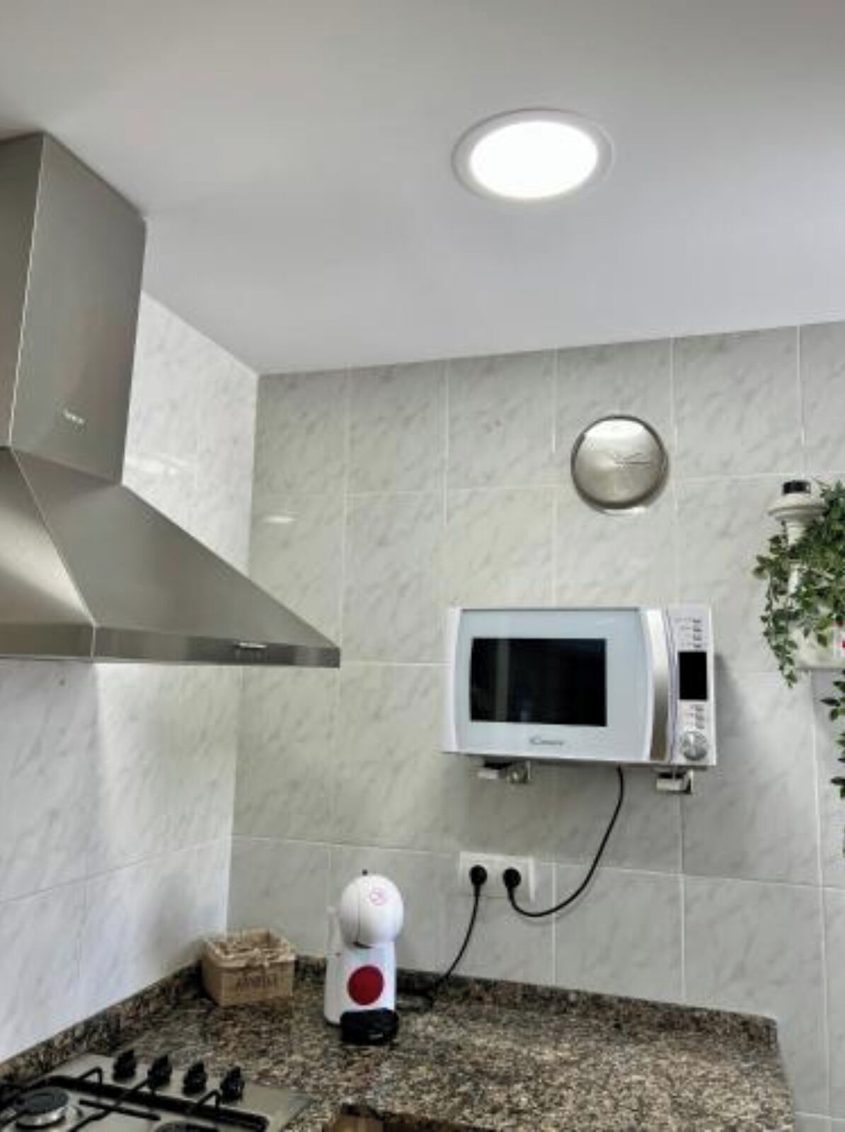 A kitchen with a microwave, gas stove, and a coffee maker on the counter.