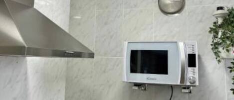 A kitchen with a microwave, gas stove, and a coffee maker on the counter.