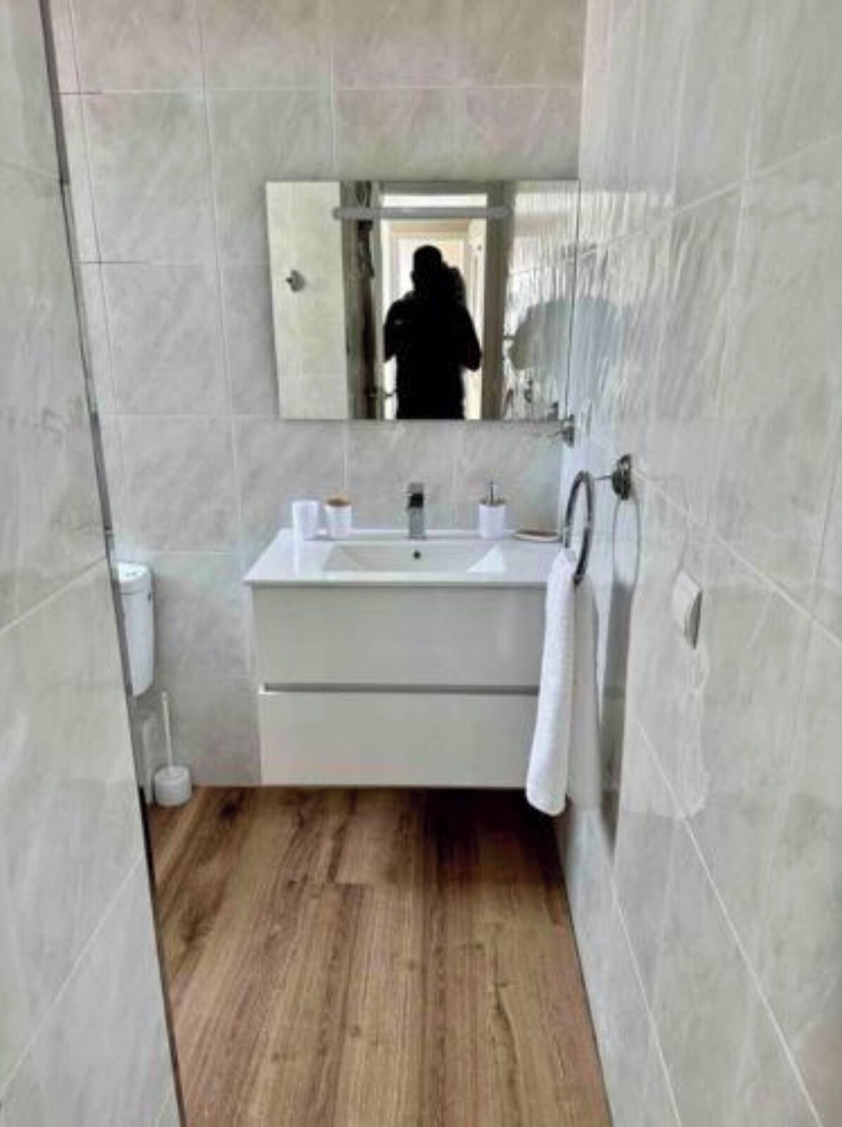 A modern bathroom with a sink, mirror, and towel rack.