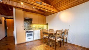Une cuisine avec des meubles en bois, un pare-feu en carrelage et un coin repas comprenant une table et des chaises.