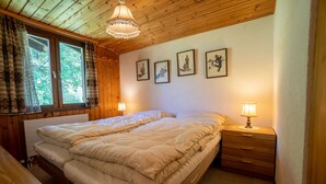 Une chambre confortable avec un plafond en bois, un grand lit avec deux oreillers, une table de chevet avec une lampe et une fenêtre avec des rideaux.