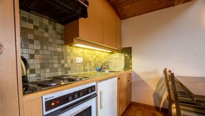 Une cuisine compacte équipée d’une cuisinière, d’un four et d’un plan de travail recouvert de carreaux.