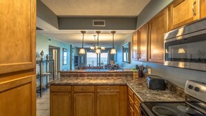 A kitchen with wooden cabinets, granite countertops, stainless steel appliances, and pendant lighting.