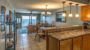 A spacious kitchen with a large island, wooden cabinets, and a view to the outside.