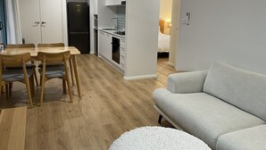 Eine moderne Wohnung mit Essbereich, einer Küchenzeile und einem Wohnzimmer mit einer Couch und einem weißen Teppich.