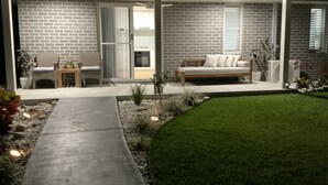 Ein modernes Haus mit Terrasse, einer Couch und einem Essbereich.