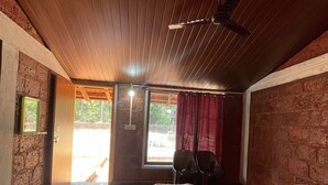 Quarto com cama, ventilador de teto, janela com cortinas e vista para o exterior.