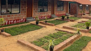 Fileira de edifícios de tijolo com grandes janelas e um jardim com plantas em vasos.
